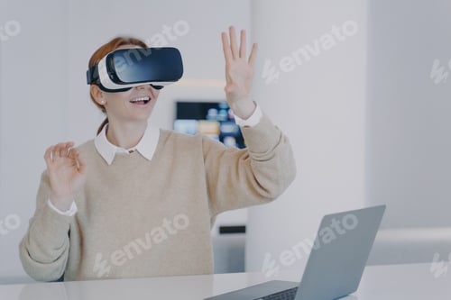 Preview: Young european girl in VR headset is gesturing concentrated on her vision. Futuristic remote work.