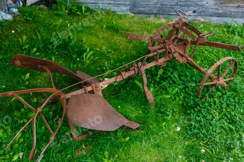 Preview: old rusty plow lying on the grass