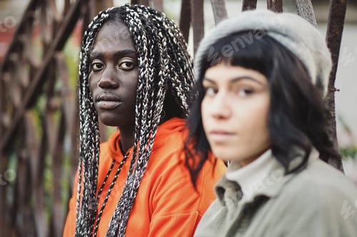 Preview: Biracial girlfriends standing outdoors next to a gate