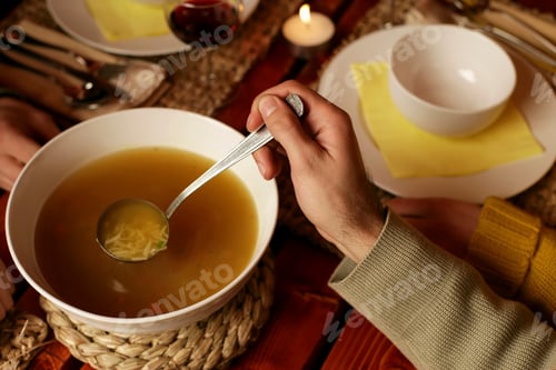 Preview: Cozy dinner setting with a person enjoying a bowl of hot soup by candlelight