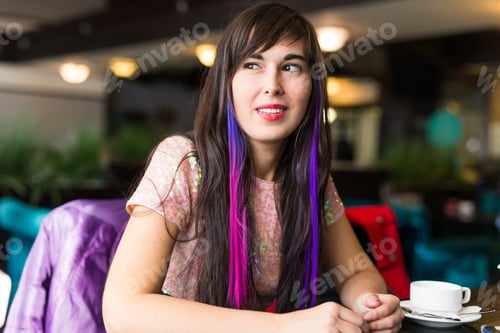 Preview: Young stylish trendy woman with multi-coloured strand in hair sits in cafe