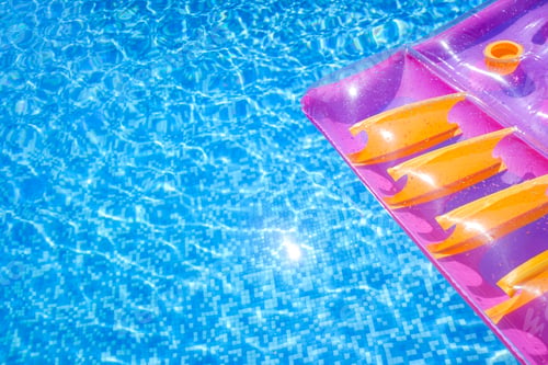 Preview: Transparent water from a pool, background with summer colored floats.