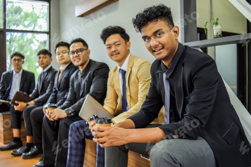 Preview: Group Portrait Of Young Businessmen Smiling At The Camera While Sitting At Office Space