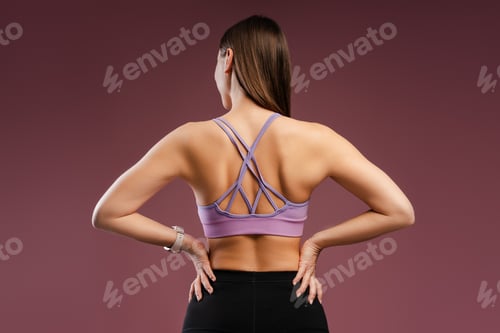 Preview: Young Caucasian woman wearing sporty uniform showing back muscle, back view
