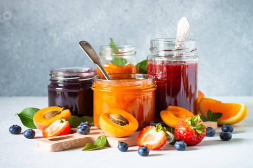 Preview: Homemade jam in glass jars at white table.