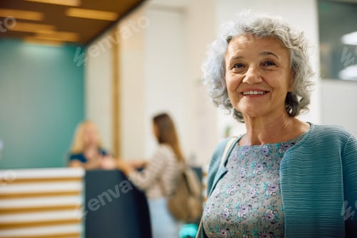 Preview: Portrait of happy elderly woman in hallway at medical clinic.