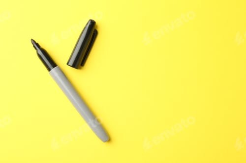 Preview: One black marker on yellow background, top view. Space for text