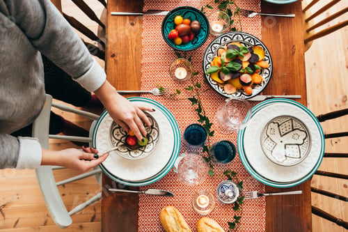 Preview: Low section of woman arranging food in bowl on laid table