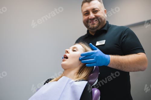Preview: Male doctor orthodontist-gnathologist palpates the jaw joints of the female patient