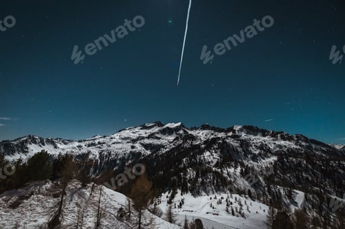 Preview: Vertical photo of snow-capped mountains at night with stars and a meteor in the sky
