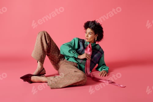 Preview: Young beautiful woman poses elegantly in colorful fashion on pink background