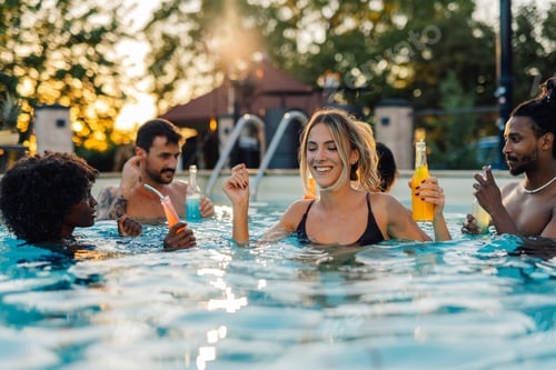 Preview: Friends enjoying drinks in swimming pool at sunset party