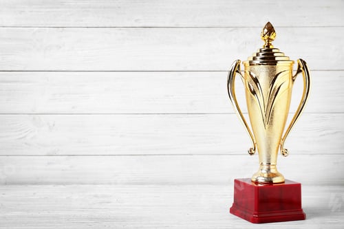 Preview: Golden trophy cup on white wooden background. Space for text