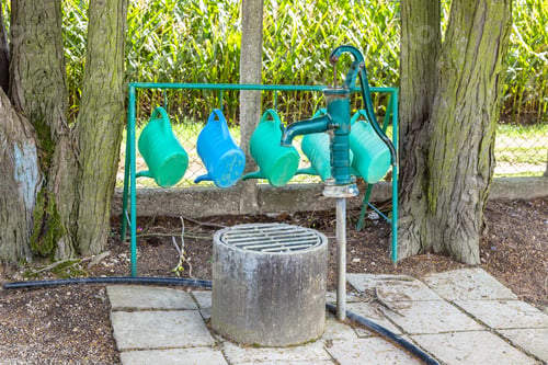Preview: Watering cans hanging near water pump at cemetery