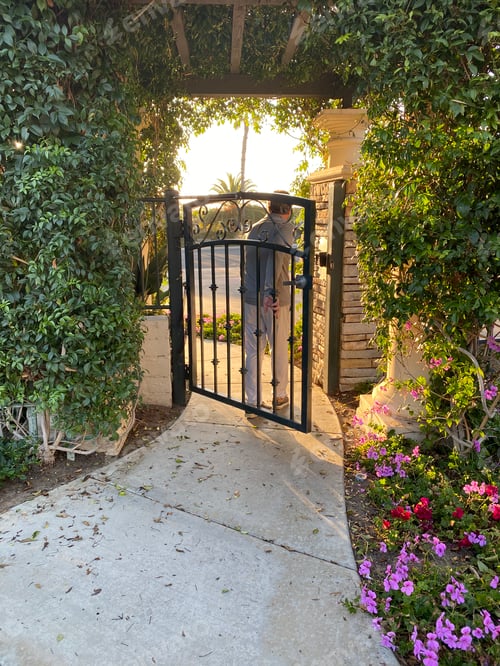 Preview: A baby boomer man walks through the gate of a secure protected gated community at sunset