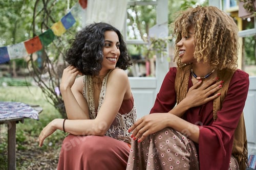 Preview: smiling young african american woman talking to multiracial friend outdoors in retreat center