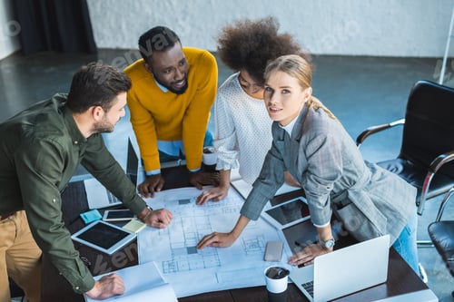 Preview: high angle view of multicultural businesspeople working with blueprint in office