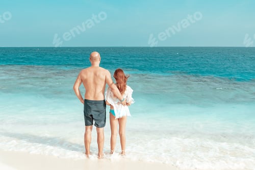 Preview: red haired cute teenage girl in swimsuit and young man father stand on shore of the Indian Ocean in
