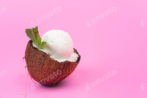 Preview: Vanilla ice cream balls in fresh coconut halves, decorated with mint leaves on a pink background