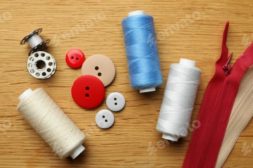 Preview: Flat lay composition with spools of threads and sewing tools on wooden table