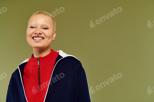 Preview: Brightly dressed young bald woman revealing joy in front of a vibrant green backdrop