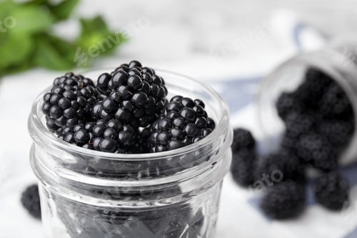 Preview: Glass jar of tasty ripe blackberries on table, closeup