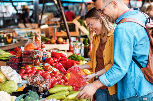 Preview: Young couple buying fresh vegetables on outdoor market.
