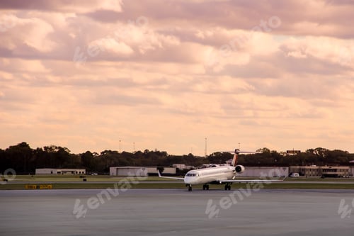 Preview: Airport view of airplane leaving departure gate ready to take of to its destination & sunset sky