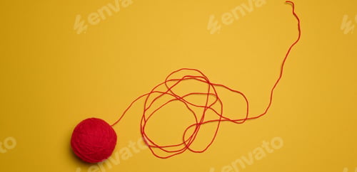 Preview: A ball of red woolen threads on a yellow background