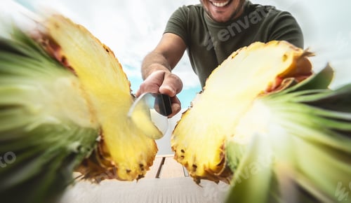 Preview: Young smiling man cutting pineapple