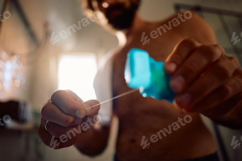Preview: Close up of man cleaning his teeth with dental floss.