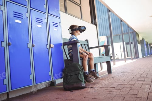 Preview: Full length of boy using virtual reality glasses while sitting on bench
