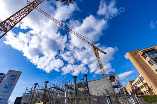Preview: Low angle shot of cranes and a building infrastructure under a blue sky on a construction site