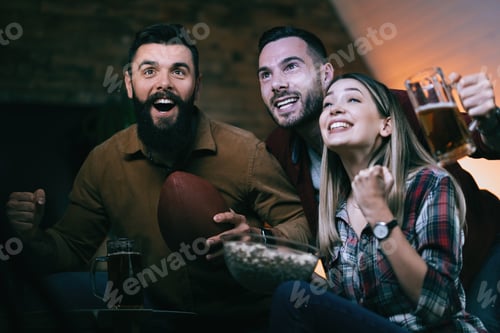 Preview: Excited friends cheering for rugby team while watching sports match on TV.