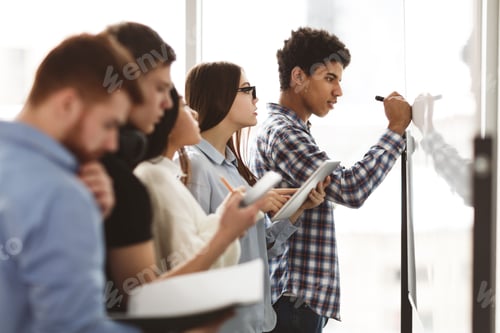 Preview: Male high school pupil writing on whiteboard in class