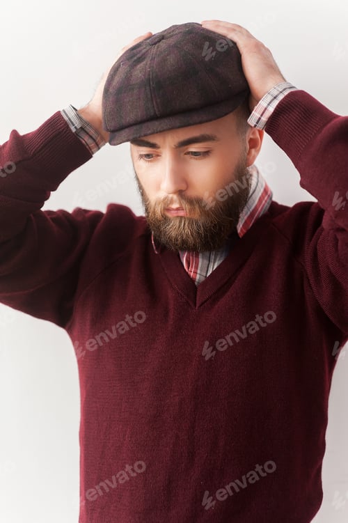 Preview: Stylish handsome. Handsome young man in casual wear touching his hat with hand and looking away