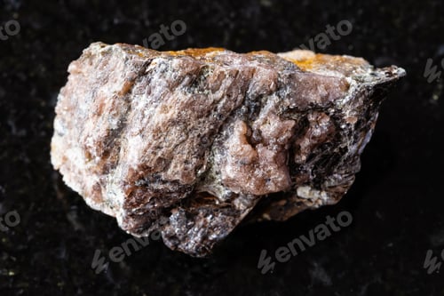 Preview: sample of raw andalusite rock on black granite