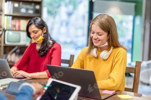 Preview: Two young women studying in library together, preparing for exams