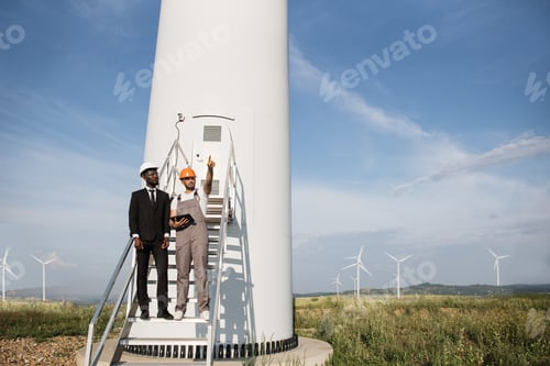 Preview: Engineer and businessman using tablet for wok with windmills
