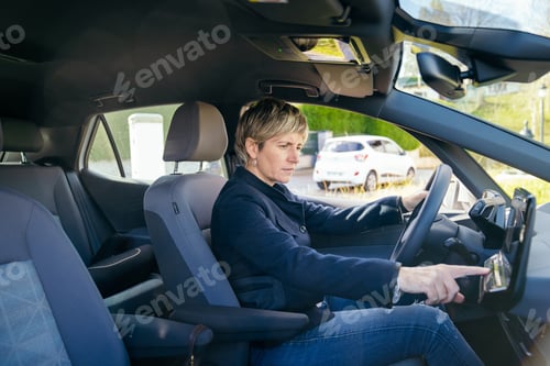 Preview: Woman driver operating modern car dashboard controls