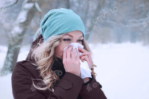 Preview: woman blowing her nose in winter