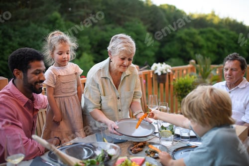 Preview: Multigenerational family eating dinner at barbecue party.