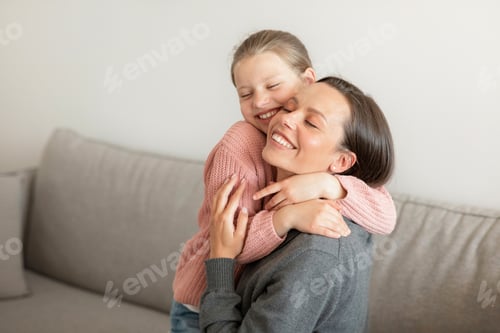 Preview: Cheerful happy cute european teen girl hugging millennial mom, have fun, enjoy spare time in living
