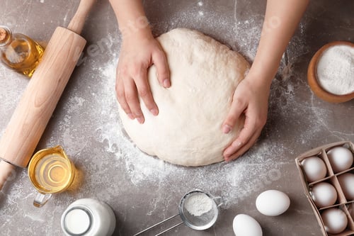 Preview: Female baker preparing bread dough at kitchen table, top view