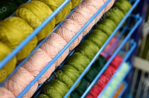 Preview: rows of balls of colorful cotton yarn threads for knitting pale pink and green colors on the shelves