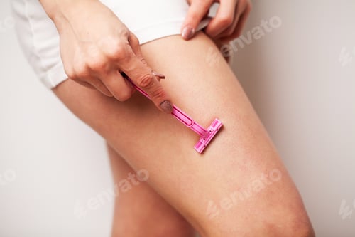 Preview: Woman shaves her legs with a razor in the bathroom in a home apartment