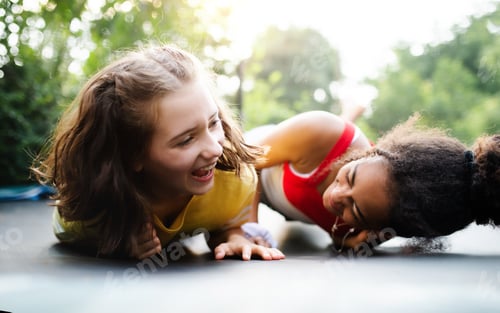 Preview: Front view of young teenager girls friends outdoors in garden, laughing
