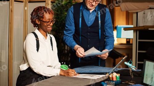 Preview: Tailor and apprentice reviewing sketches