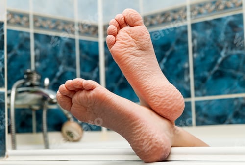 Preview: Wrinkled bare feet coming out from a bathtub.