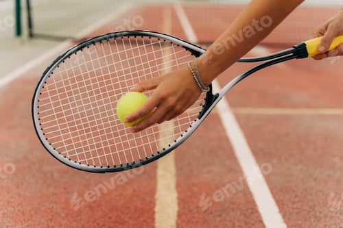 Preview: Closeup picture of beautiful sporty woman hands holding yellow tennis ball and racket with tennis